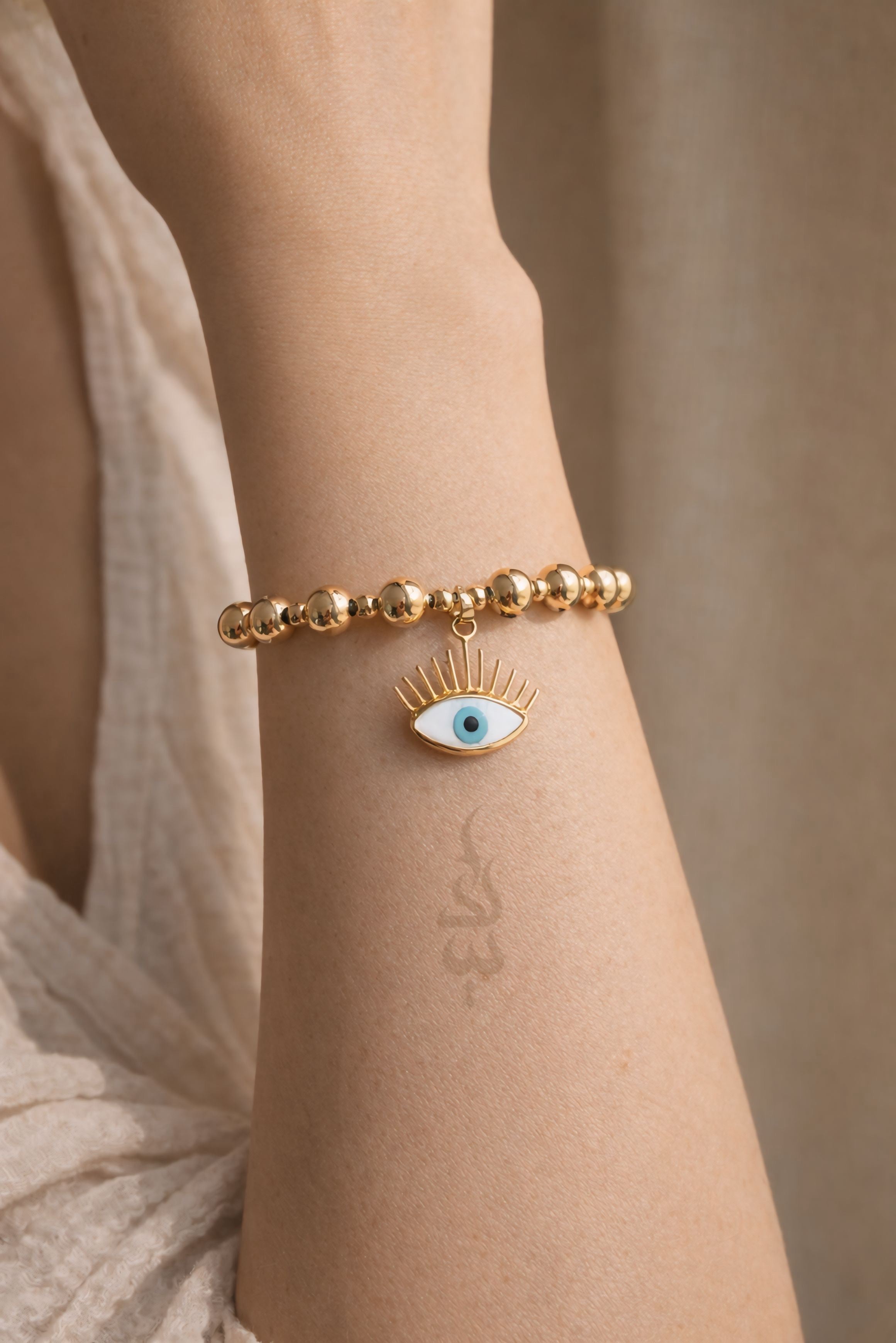 18K gold bracelet featuring polished gold beads with eye charm