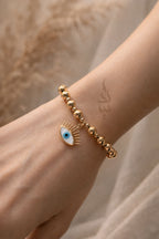 18K gold bracelet featuring polished gold beads with eye charm